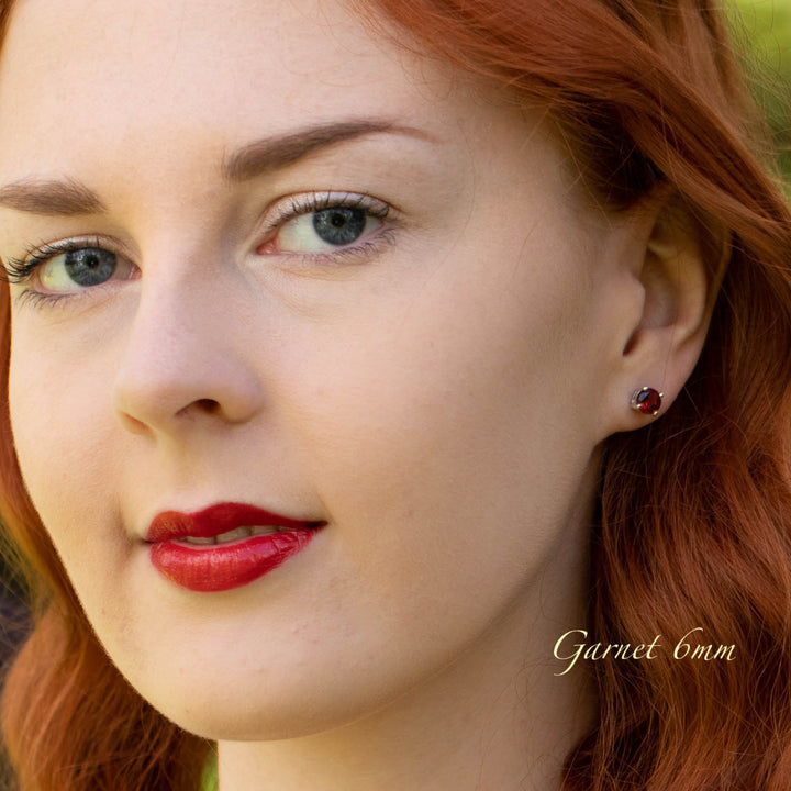 Close-up of a woman with red hair wearing a garnet earring.