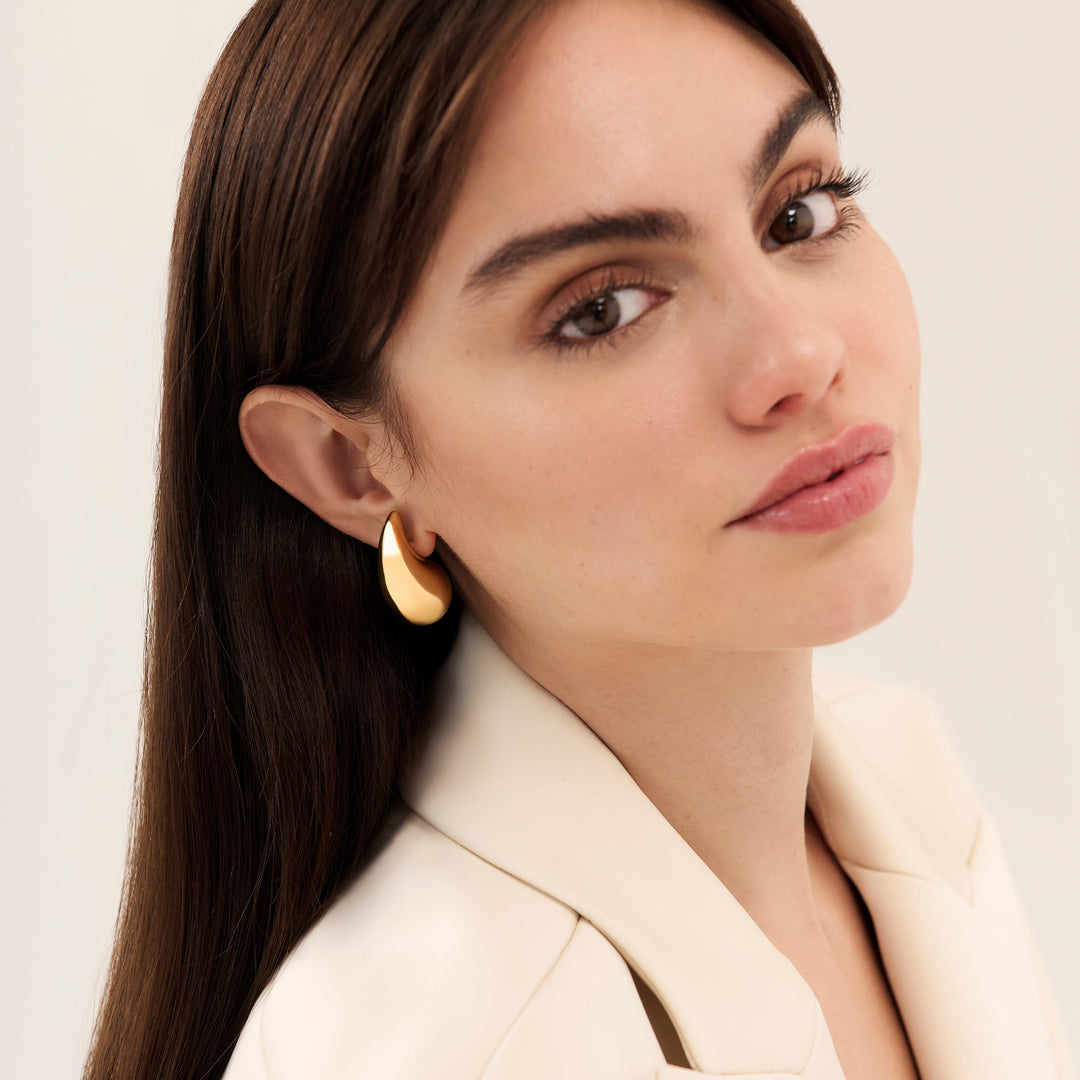 Chunky gold teardrop earrings in 18K gold PVD over 316L stainless steel, worn by a model