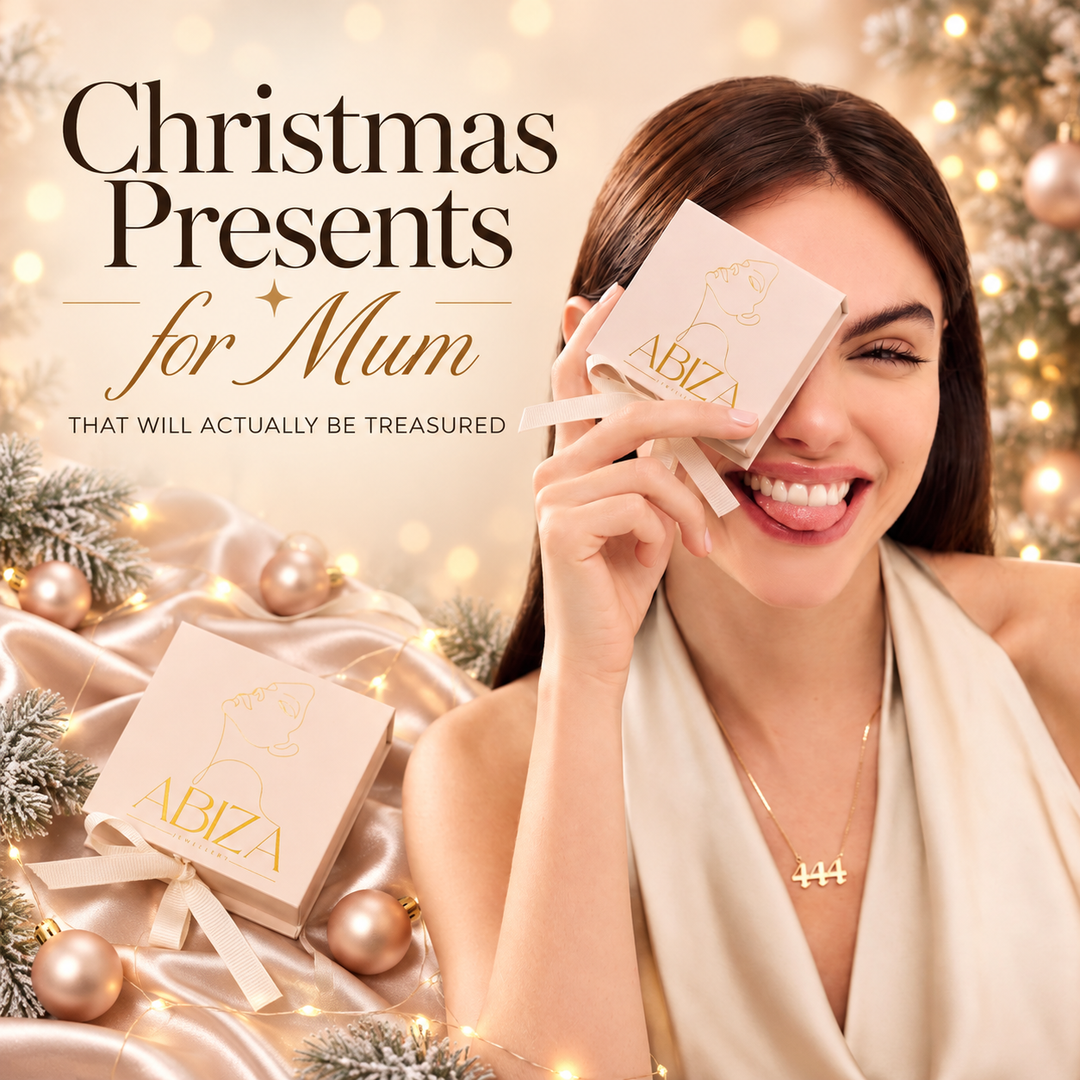 Christmas Presents for Mum that will actually be treasured — a woman holding an Abiza gift box to her eye beside a Christmas tree, wearing a gold 444 angel number necklace