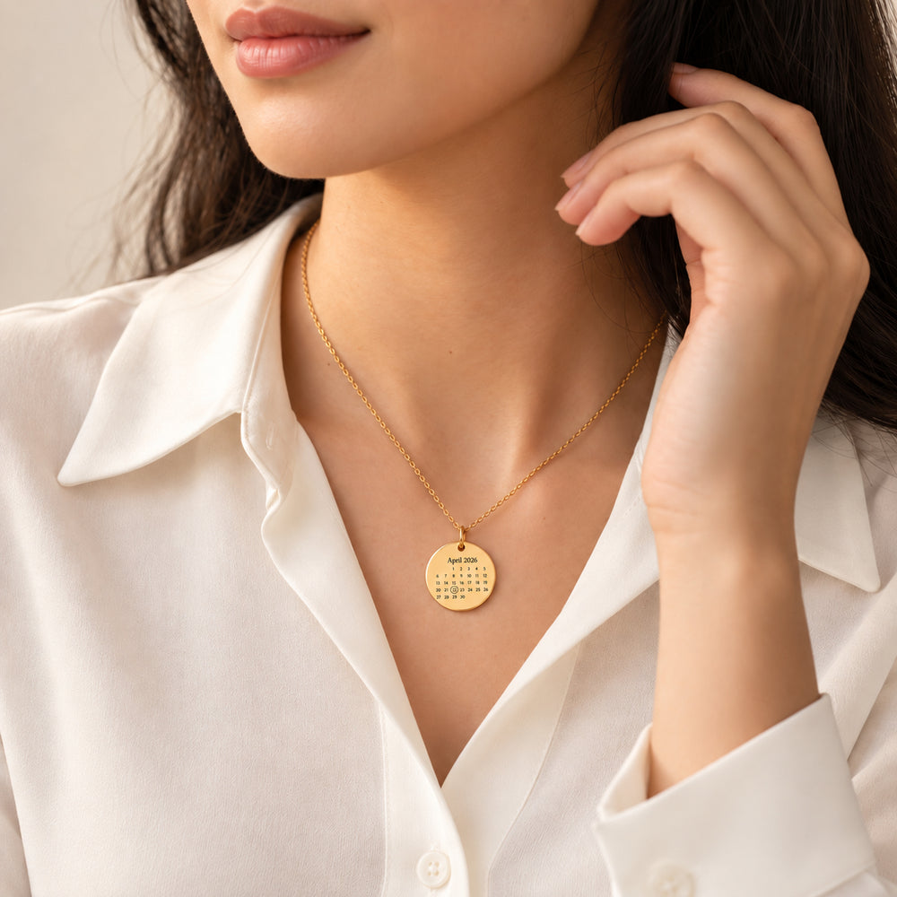 Woman wearing a gold calendar necklace engraved with April and a circled date