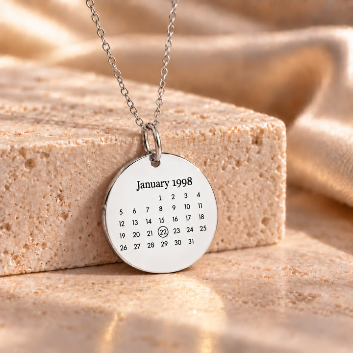 Silver stainless steel calendar necklace with an engraved month and circled date