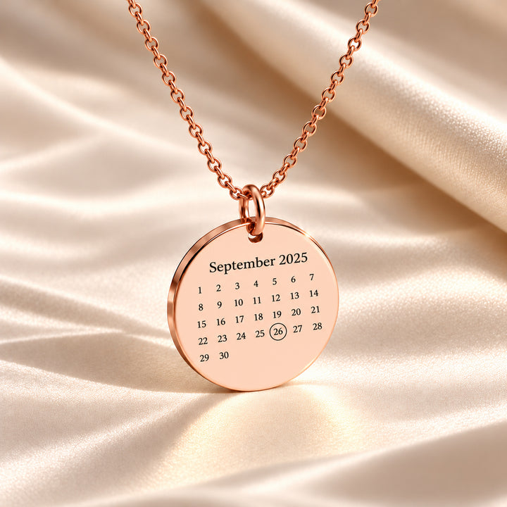 Rose gold calendar necklace engraved with September 2025 and the date circled