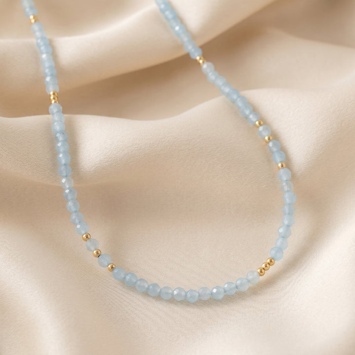 Real aquamarine necklace flat lay — sea-blue 3mm diamond-cut detail, hand-strung close-up