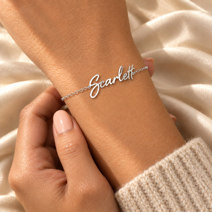 Silver script name bracelet worn on the wrist, name cut in flowing script