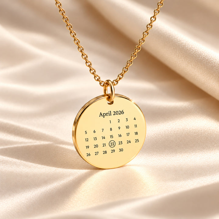 Gold calendar necklace engraved with April 2026 and the 22nd circled