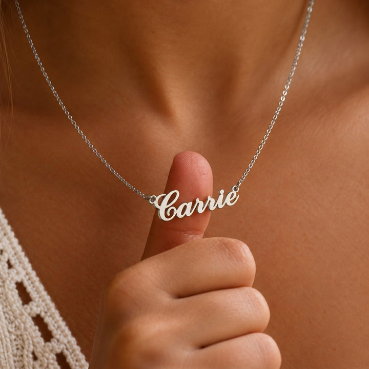 Silver Carrie name necklace held on model, classic script nameplate