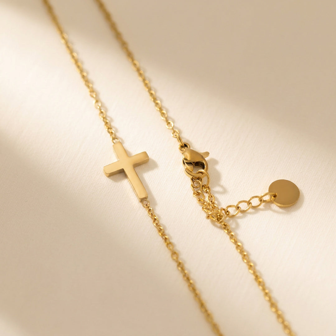 Gold sideways cross necklace showing the lobster clasp and extender chain