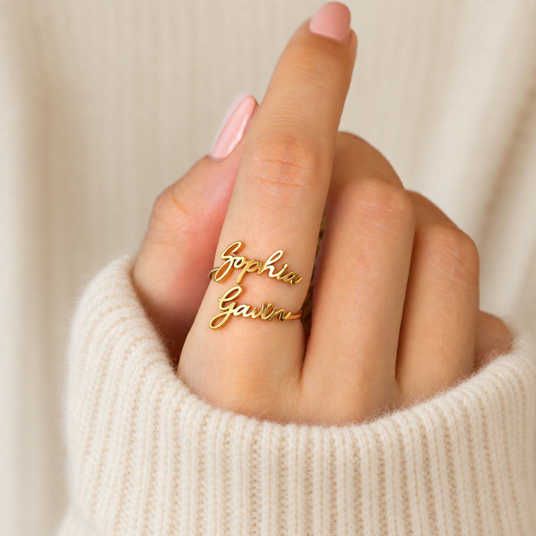 Gold personalised name ring with two names in script, worn on a hand