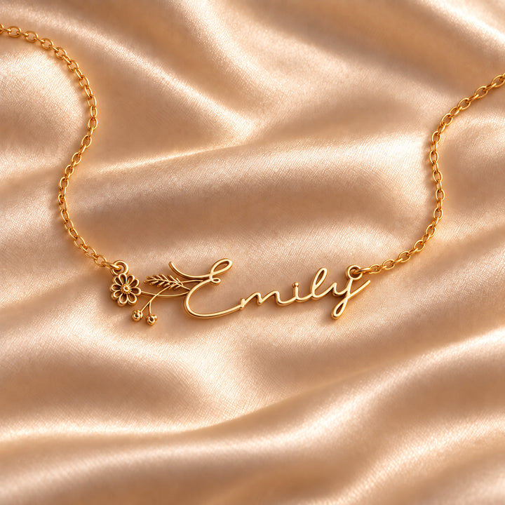 Gold birth flower name necklace with the name Emily and a daisy, flat lay on satin
