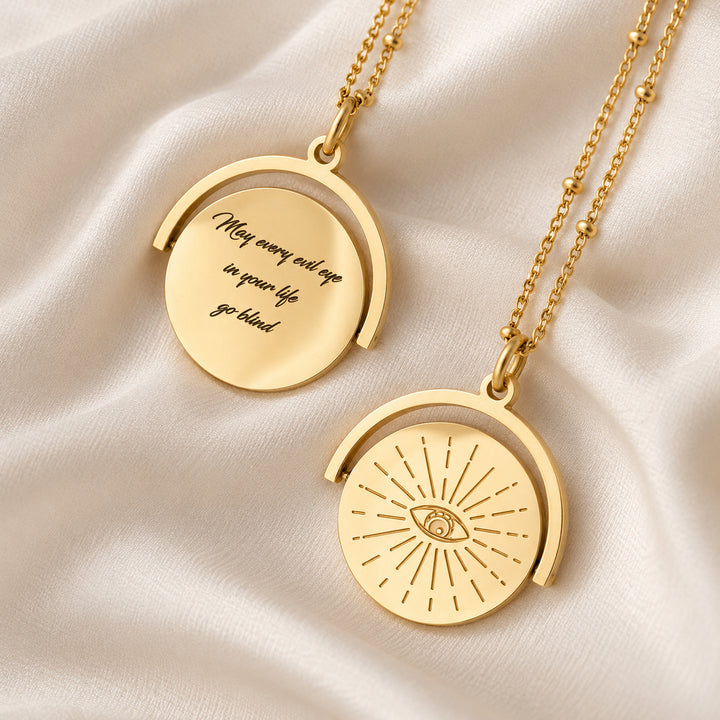 Evil eye spinner necklace — sunburst eye on one side, engraved message on the other