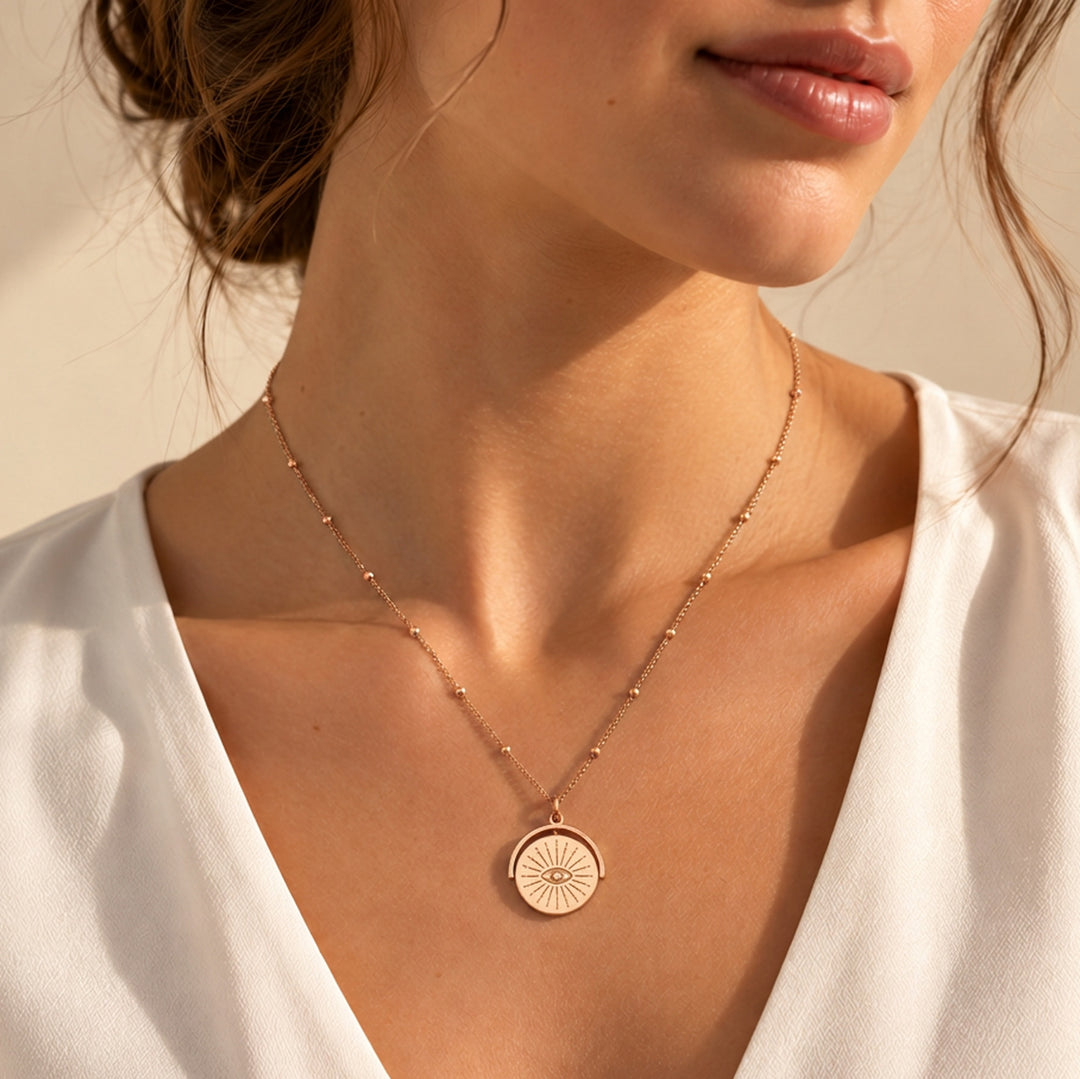 Model wearing a rose gold evil eye spinner necklace on a beaded chain