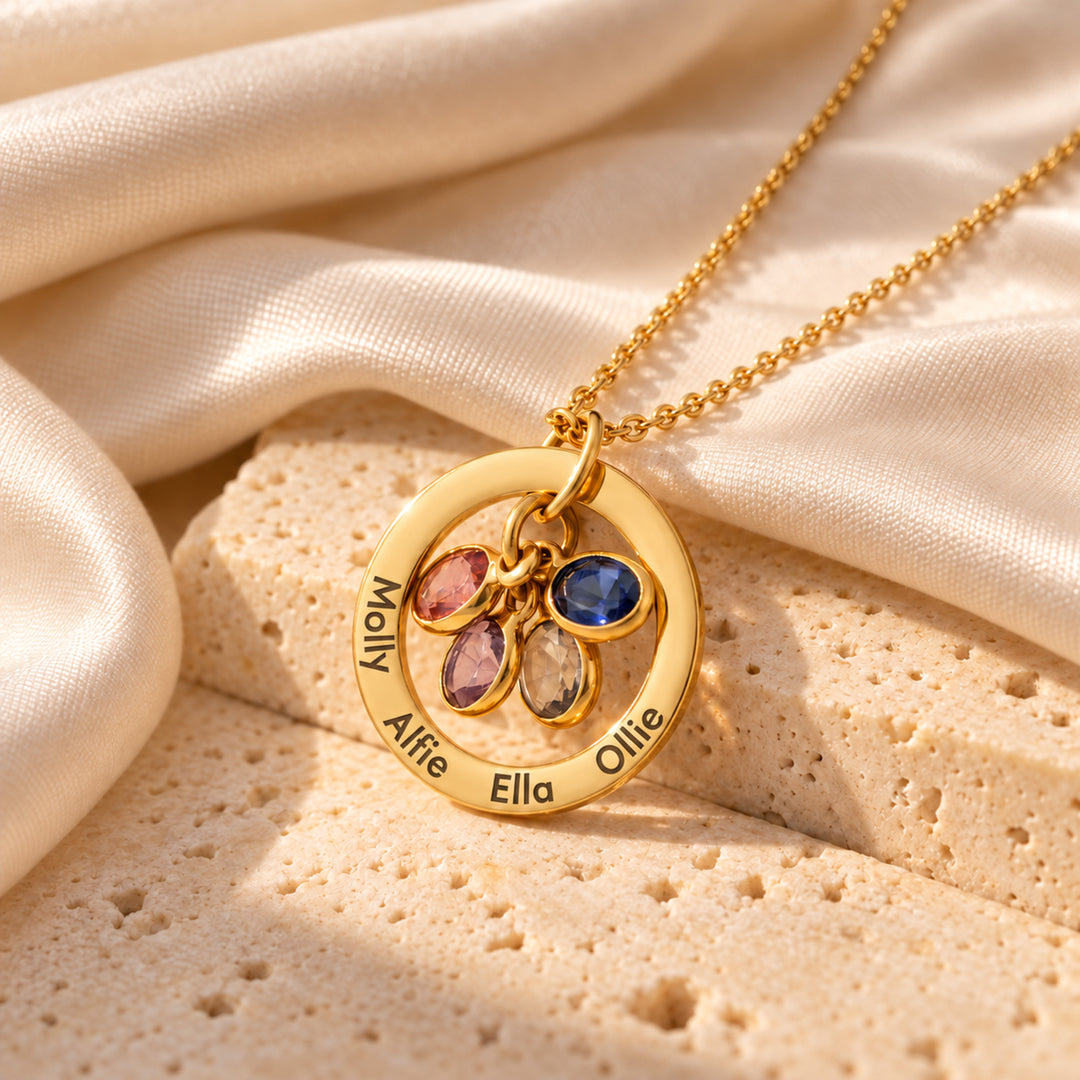 Gold family birthstone necklace with four names engraved around the ring and four birthstone charms inside