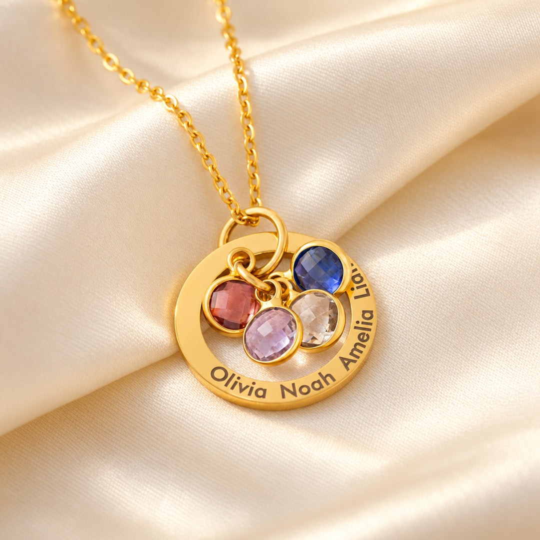 Close-up of a gold family birthstone necklace with four engraved names and four birthstone charms