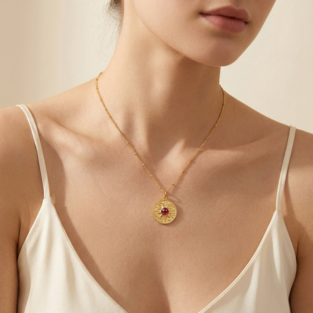 Gold garnet sun necklace worn on chain — January birthstone gift