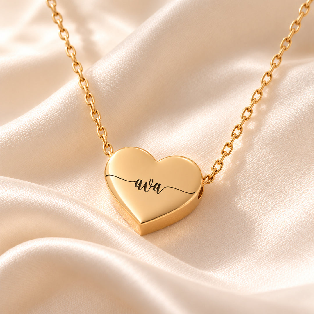 Close-up of a gold heart name necklace engraved with the name Ava