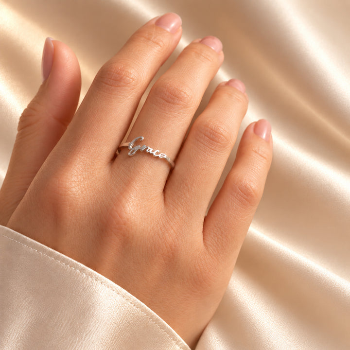 Silver personalised name ring with the name Grace in script, worn on a hand