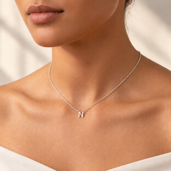 Model wearing a dainty silver initial necklace with a hanging letter N pendant
