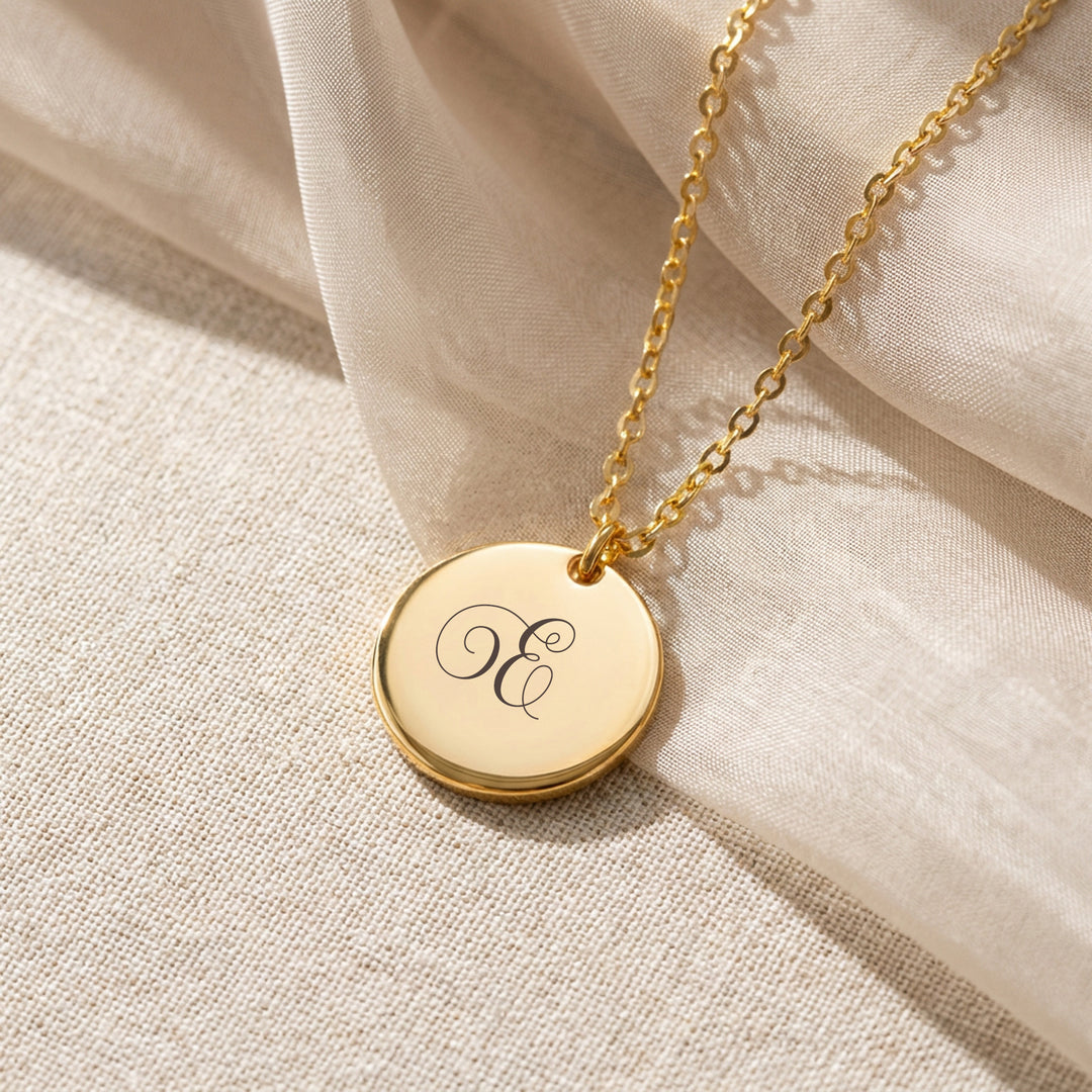 Gold initial disc necklace with engraved script letter E