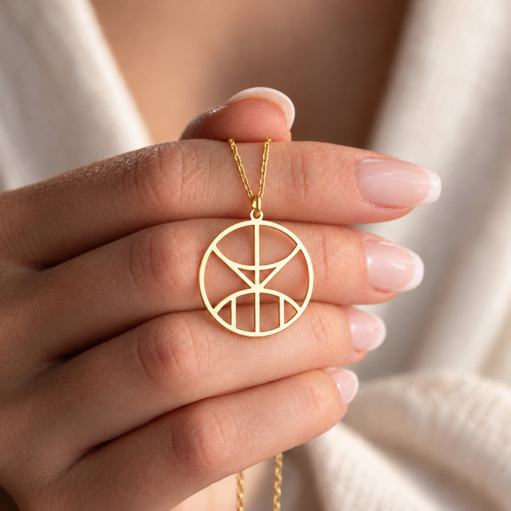 Gold monogram name necklace held in hand, showing the cut-out letter design