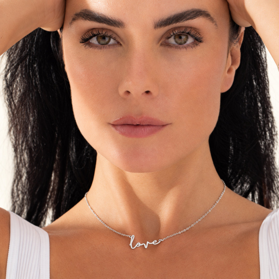 Model wearing a silver love script necklace