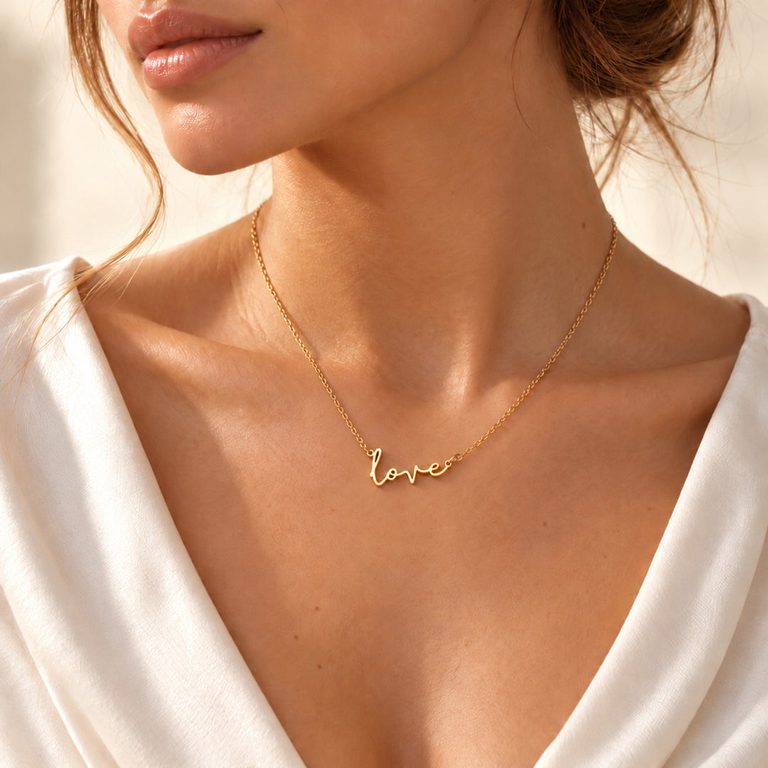 Model wearing a gold love script necklace with love written in flowing script