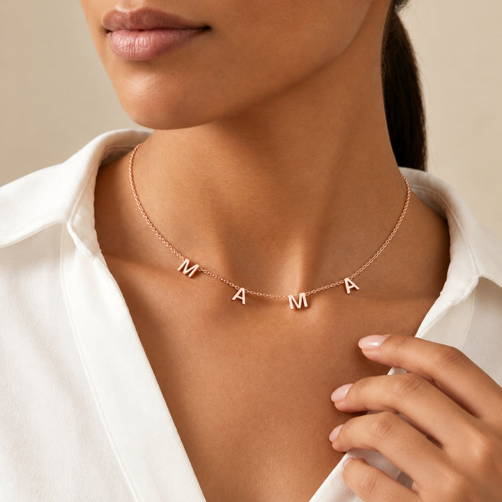 Model wearing a rose gold MAMA letter necklace with four separate letter charms