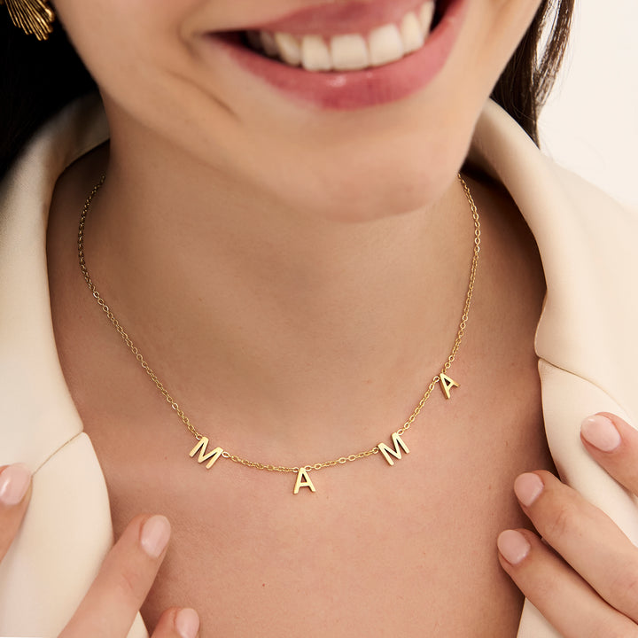 Woman wearing gold MAMA letter necklace with four letter charms