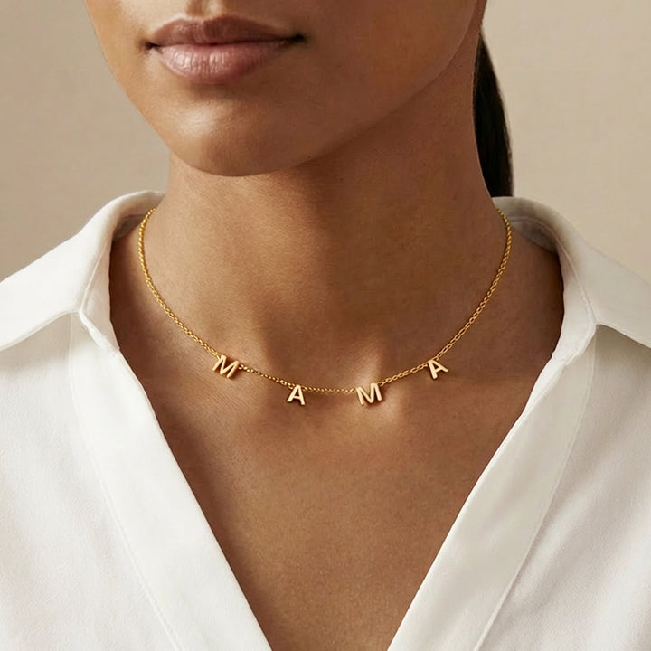 Gold 'MAMA' necklace worn by a woman with a white shirt.