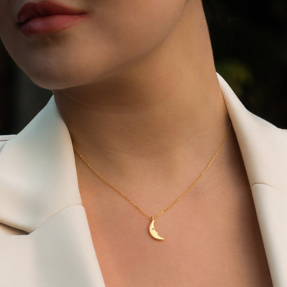 Dainty gold crescent moon necklace worn on model