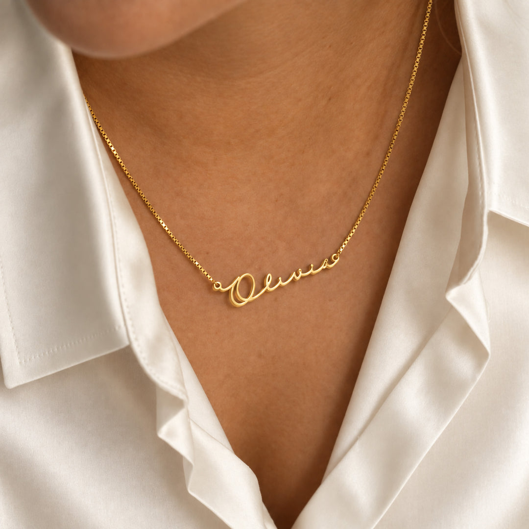 Dainty gold name necklace in fine script, worn on model