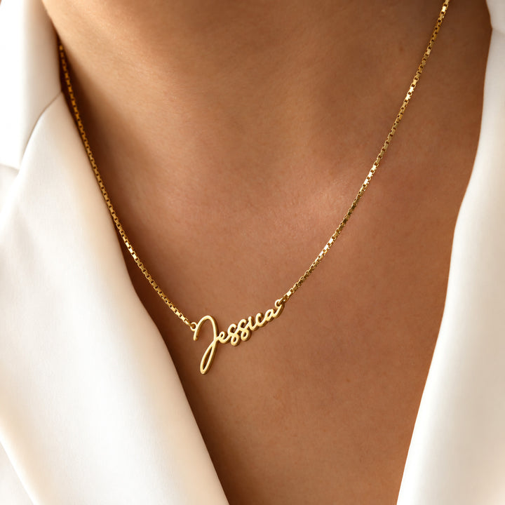 Gold name necklace in a rounded script font, worn on model