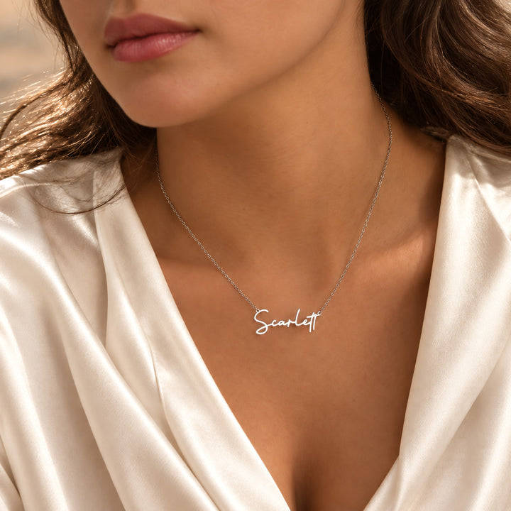 Silver name necklace in a fine script font, worn on model
