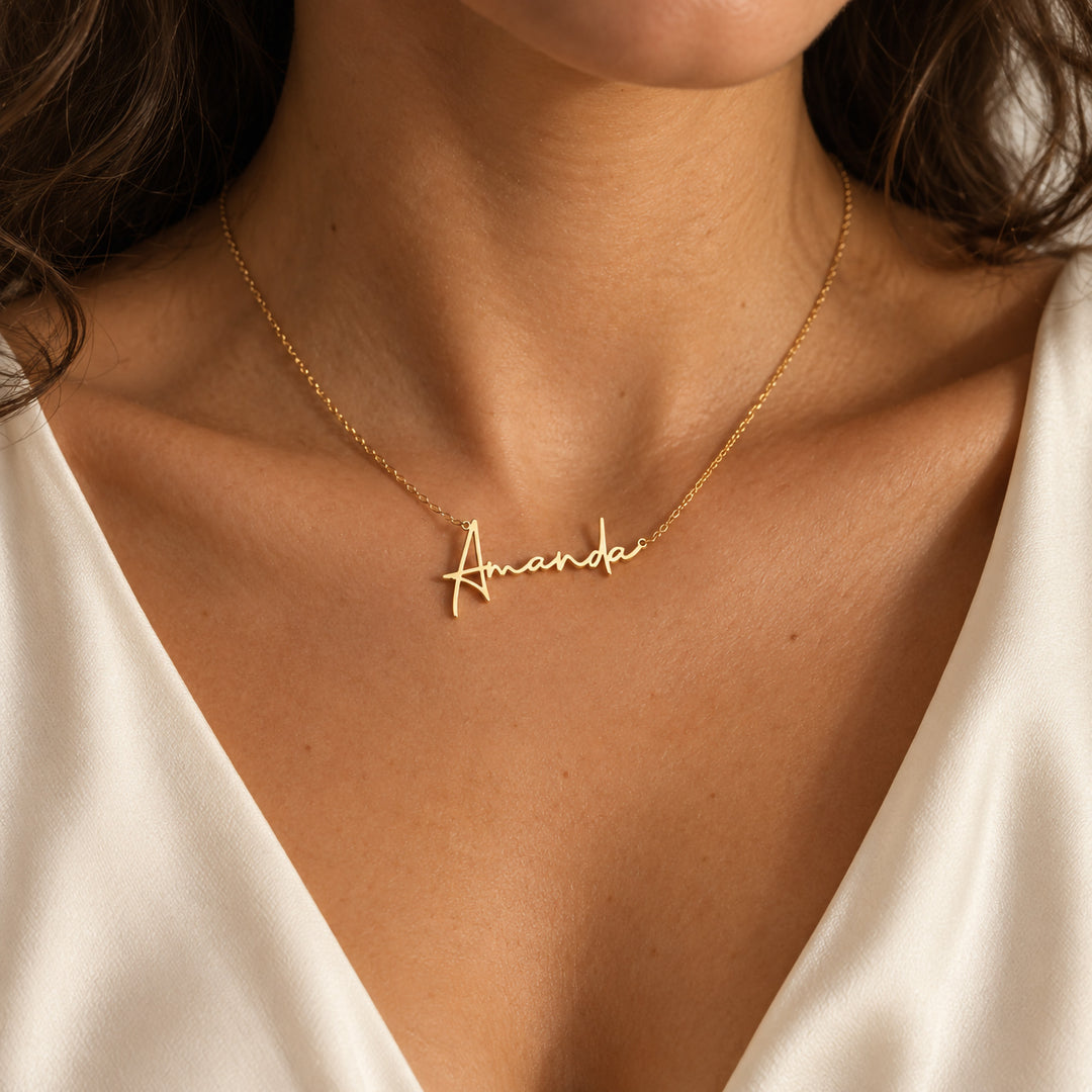 Gold personalised name necklace in flowing script, worn on model