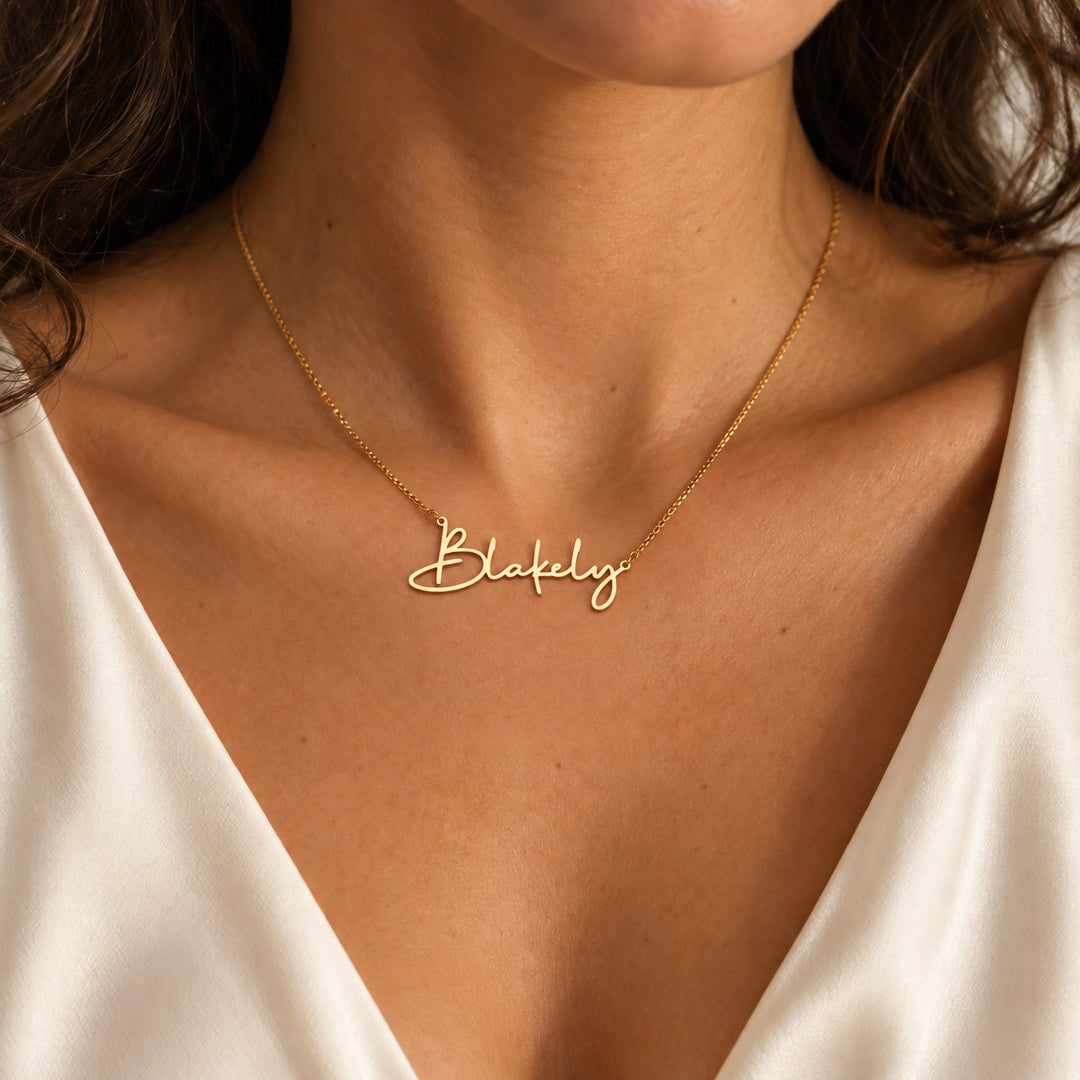 Delicate gold name necklace in script, layered under the collarbone