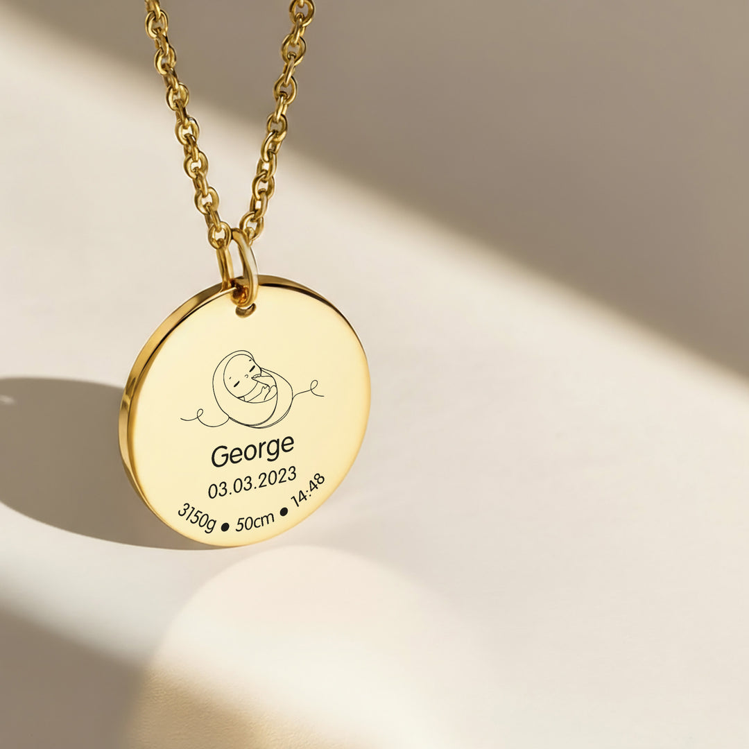 Gold necklace with a round pendant engraved with 'George' and birth details 
