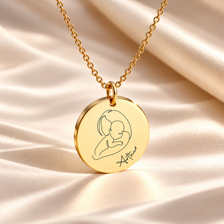 Gold baby name necklace with a mother and baby line drawing and the name Arthur