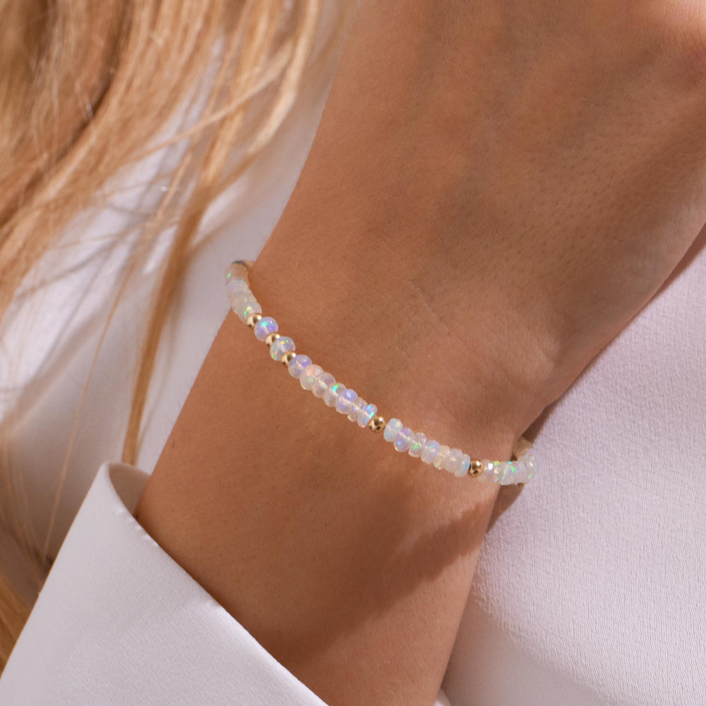 White opal bracelet on wrist — iridescent flashes of pink, green and blue