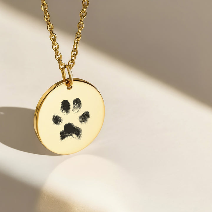 Gold round pendant engraved with pet paw print