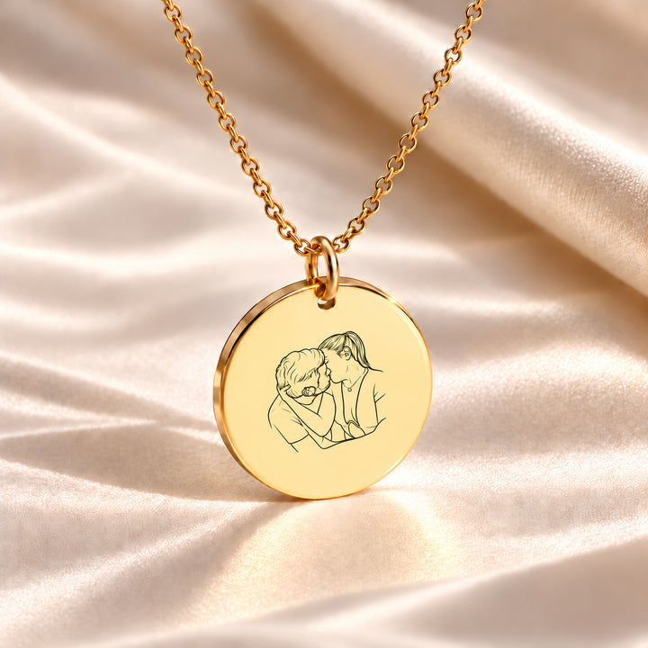 Gold photo necklace engraved with a line art drawing of a couple