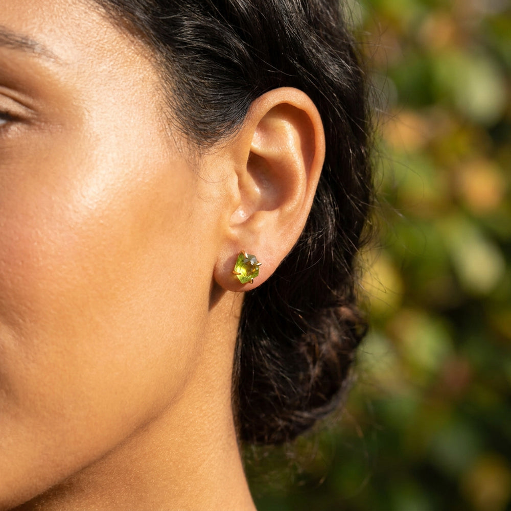Raw peridot stud earring on ear in 18K gold vermeil — natural uncut peridot crystal, August birthstone
