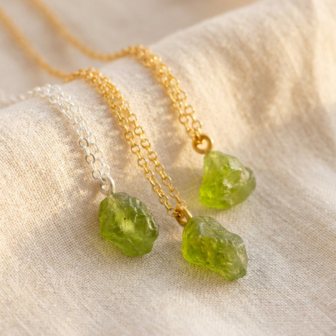 Three raw peridot stones on silver and gold PVD stainless steel chains — real August birthstone pendant necklaces from Abiza