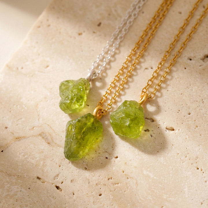 Three different raw peridot crystal pendants on silver and gold PVD chains — each stone unique in shape and colour