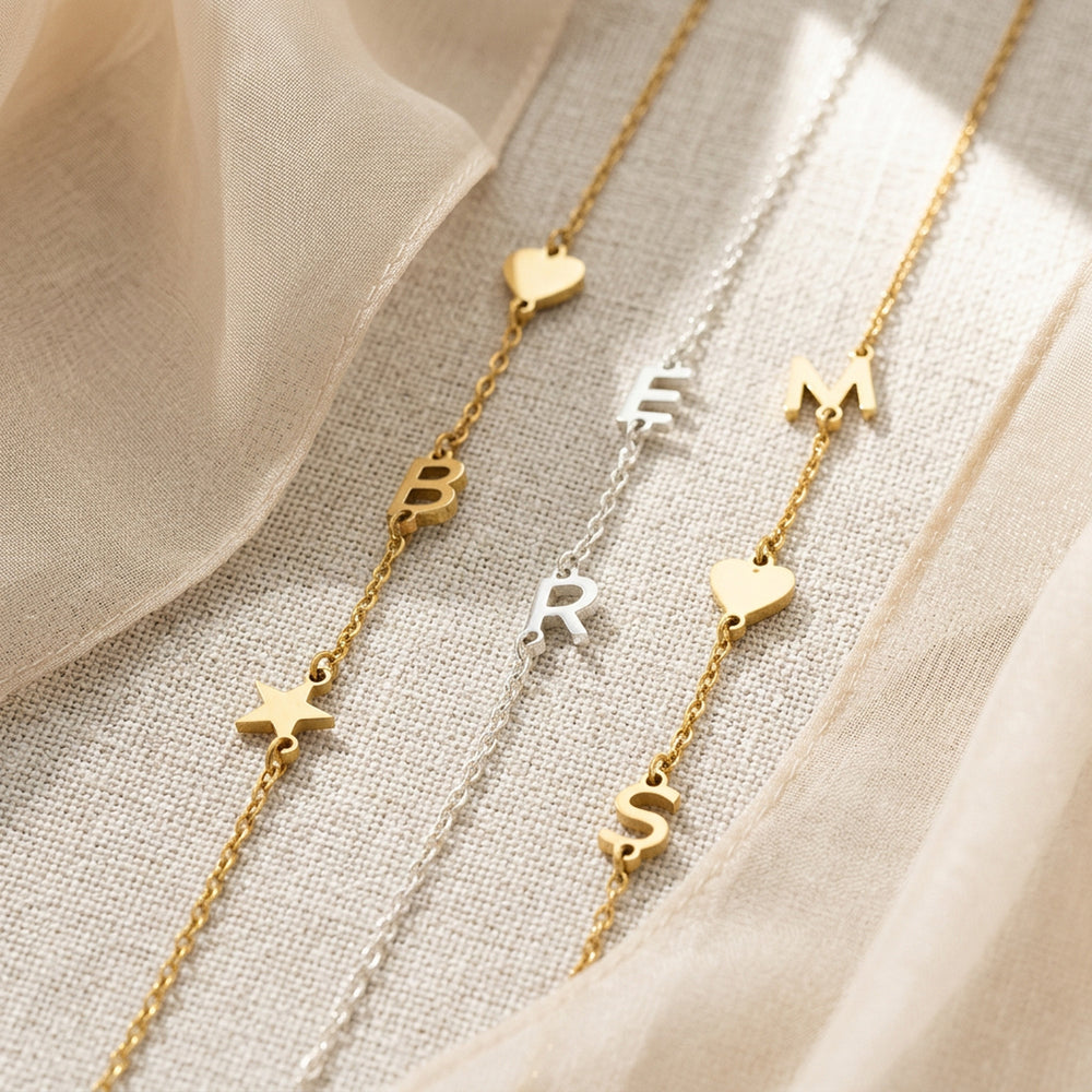 Personalised initial bracelet styled in gold and silver — letter pendants on dainty chain
