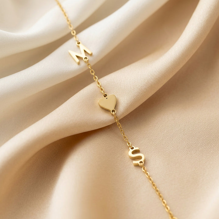 Gold initial bracelet — close-up showing letter pendants and dainty cable chain