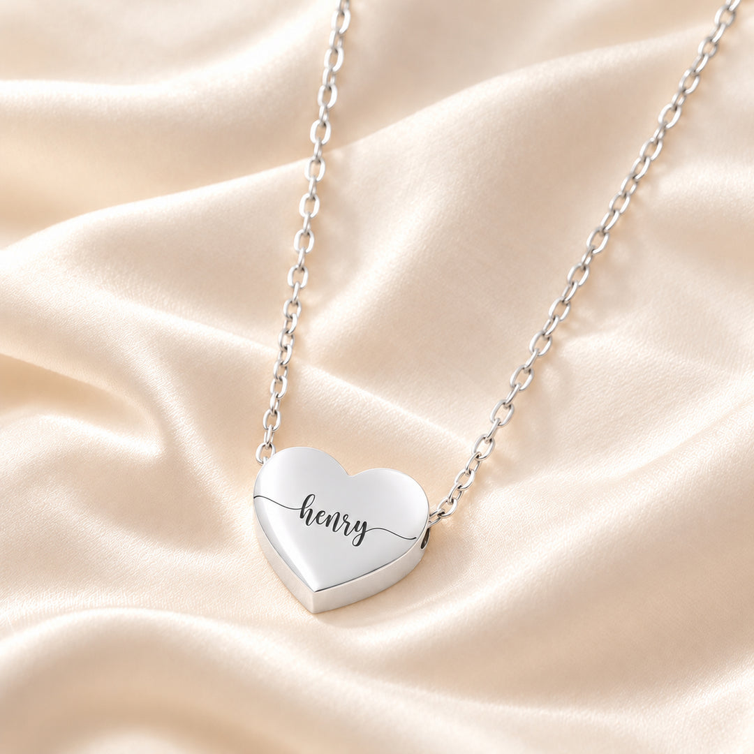 Close-up of a silver heart name necklace engraved with the name Henry