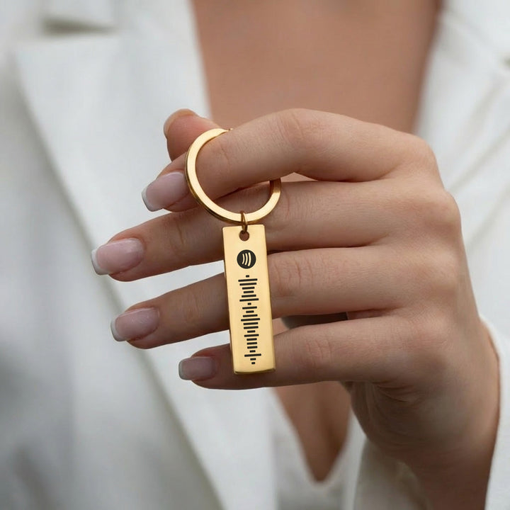 woman holding gold personalised Spotify keyring with Spotify song code
