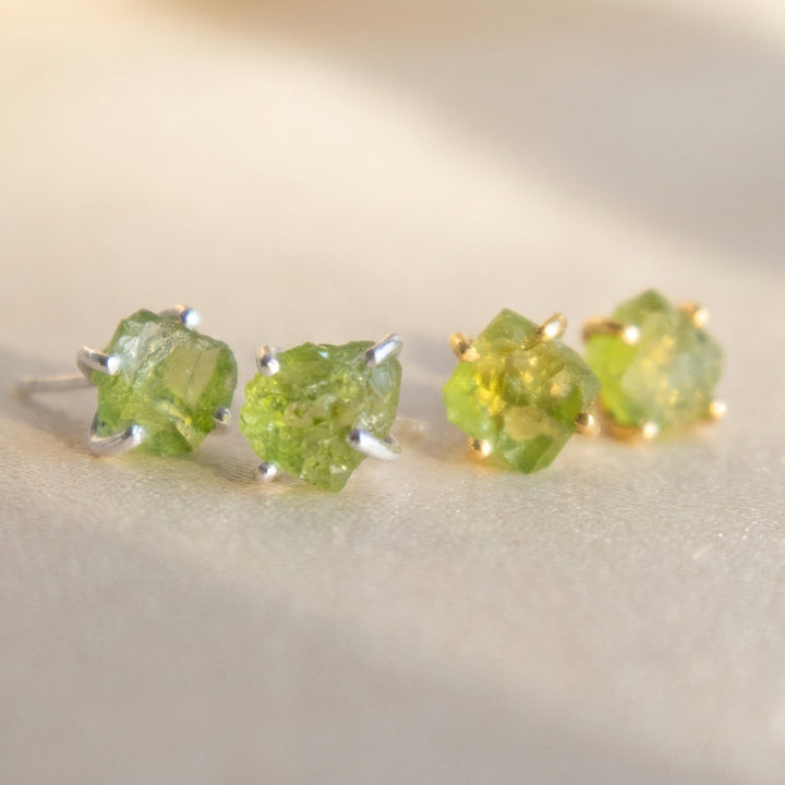 Real raw peridot stud earrings — gold and silver pairs together, natural uncut peridot crystals, August birthstone
